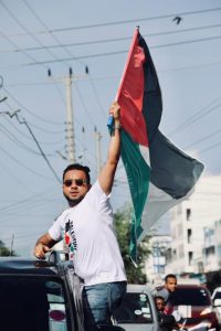 A protestor waving the Palestinian flag from a car window